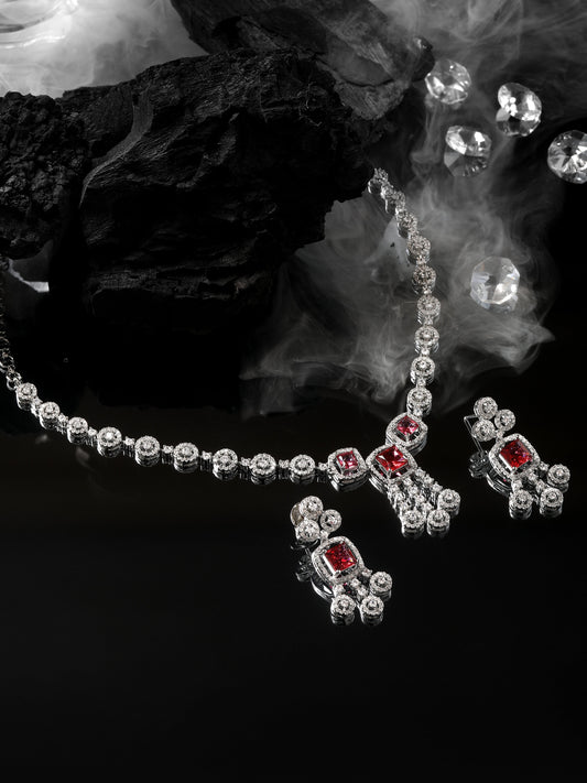 Rhodium-plated red diamond necklace set with matching drop earrings studded with cubic zirconia on black stone background