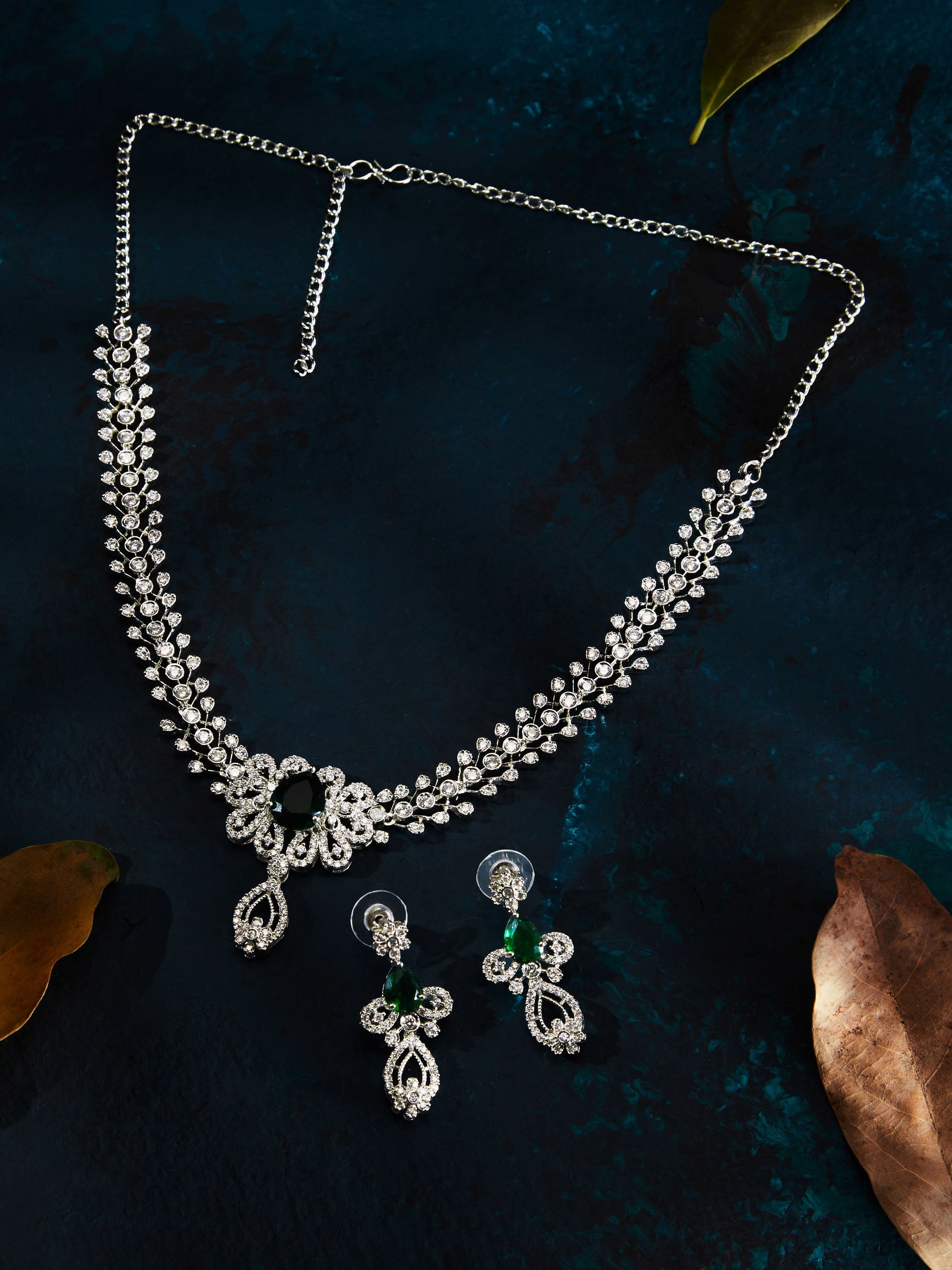 Rhodium-plated green stone diamond necklace set with floral design and matching drop earrings worn by woman