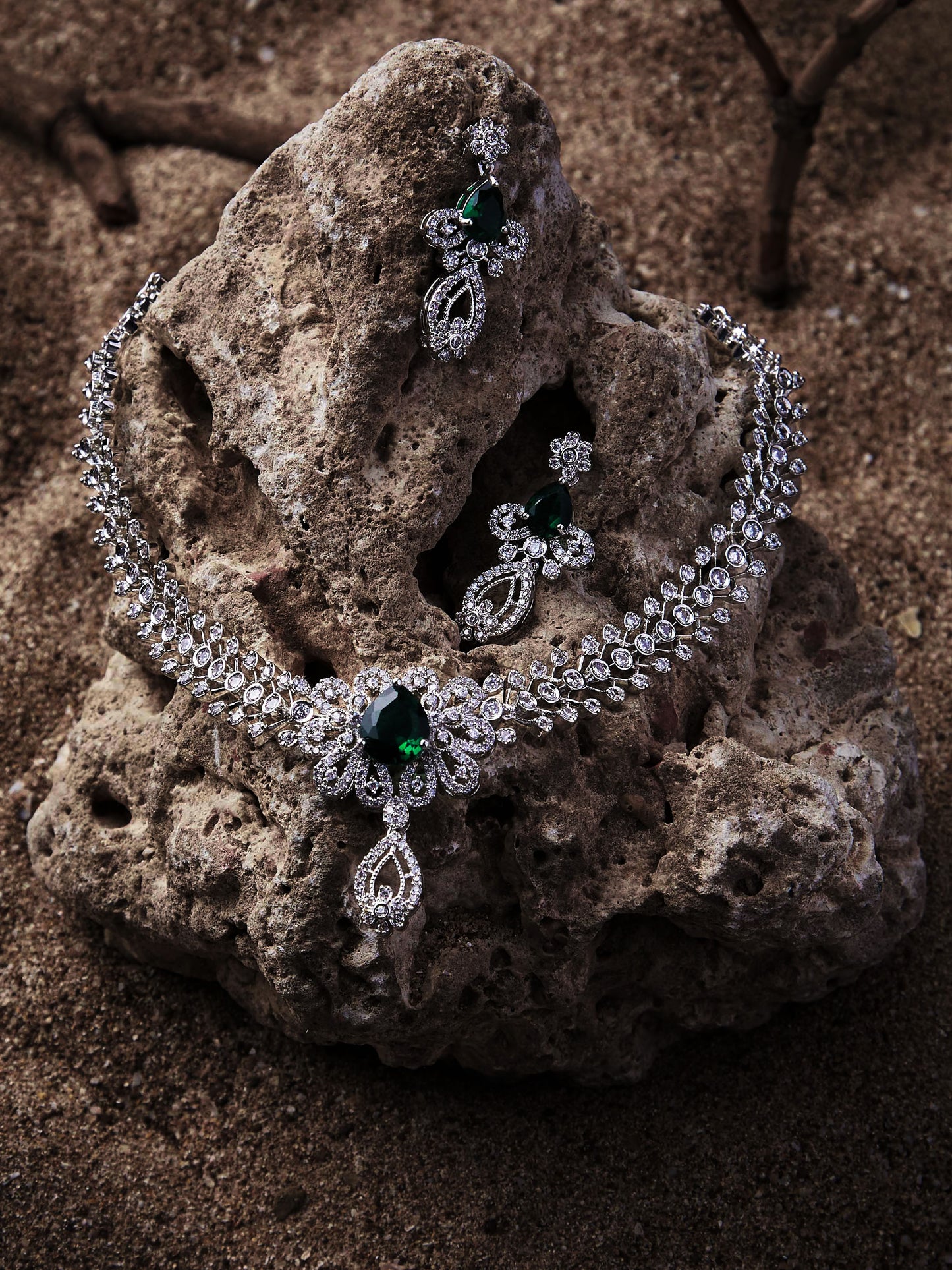Rhodium-plated green stone diamond necklace set with floral design and matching drop earrings worn by woman